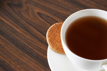 Te negro y galleta. Postre Guatemalteco sobre una mesa de madera, espacio para texto al lado izquierdo.