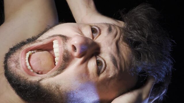 Vertical Video of Mentally ill man going crazy and shouting.
Mentally deranged man screaming and going crazy in a dark room.

