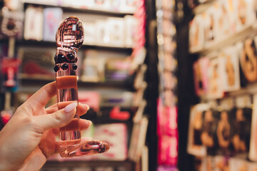 Anal glass butt plug with a fluffy tail with female hands. Toy for adult games.