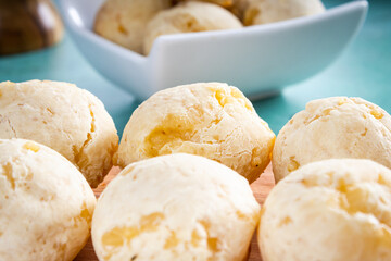 Delicioso pão de queijo, prato típico brasileiro, sobre tábua de madeira e mesa com fundo verde