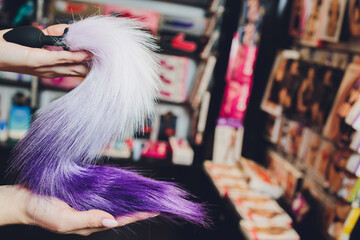 Anal mini pony plug with a fluffy tail with female hands. Toy for adult games.