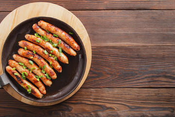 Delicious sausages cooked in a frying pan on a wooden table. copy space.