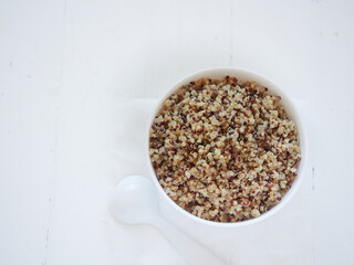 cooked quinoa, mix of varieties in white bowl, top view.