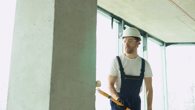 Construction worker moving paint roller on wall in new office or apartment