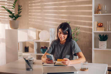 Beautiful young girl using her mobile phone for an online payment with a card.