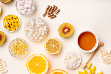 Food supplements, vitamins and minerals in form of pills, capsules and tablets. Oranges, honey and kiwi from above on bright yellow background. Healthy lifestyle. Natural vitamins from fruits.