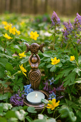 Triple Goddess Candlestick with candle on floral meadow, abstract natural background. Symbol of the...