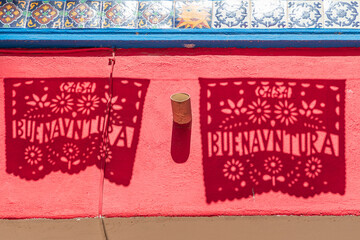 Loreto, Baja California Sur, Mexico. Shadows of banners saying 'good luck' in Spanish, in a market.