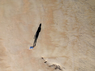 Woman walking on the beach. Aerial photo. Long shaddow.