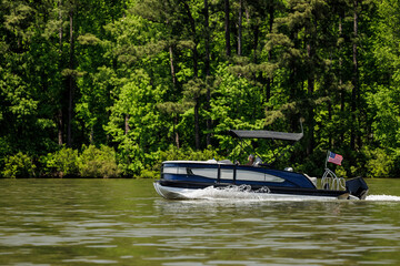 Boater on pontoon boat enjoying summer day on Lake. Pontoon party boat cruising on freshwater lake.
