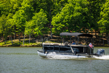 Boater on pontoon boat enjoying summer day on Lake. Pontoon party boat cruising on freshwater lake.