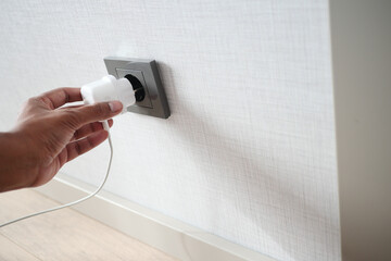  white color power cord cable plugged into wall 