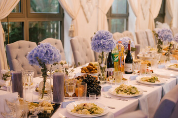 A large table is prepared for the holiday, decorated with flowers with beautiful serving and serving dishes