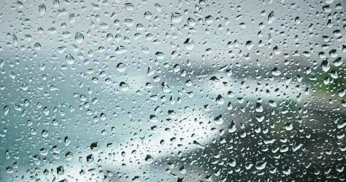 Water drops on transparent window pane during rainy weather. Severe sea crash on rocks outdooors. Stay at home. Calmness and pacification.