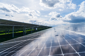 Solar panels with reflection of the sky in the solar park in sunshine with heavy clouds