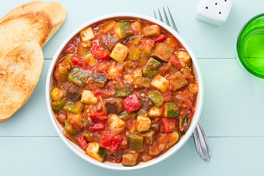 Fresh Ratatouille, a traditional French vegan vegetable stew made of eggplant, zucchini, bell pepper, tomato and onion with herbs, photographed overhead (Selective Focus, Focus on the dish)