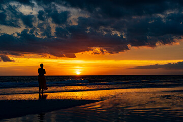 Fototapeta premium a woman watches sunset in a tropical paradise
