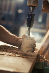 Carpenter holds birch log, uses drill press