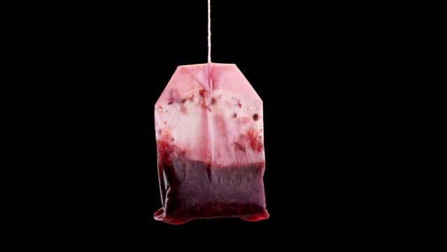 Single used teabag with tea flowing in slow motion