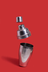 Disassembled cocktail shaker floats on a red background. Party concept