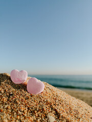 Two pink candy hearts on the beach