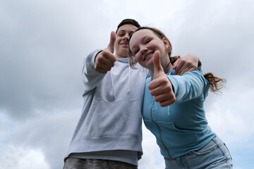 against the backdrop of a stormy cloudy sky boys teenage girls lean over showing thumbs up approval...