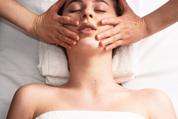 masseur doing facial massage to young woman on massage table. Concept of massage spa treatments. Close-up