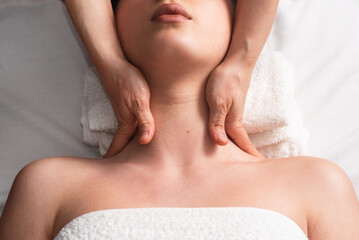 masseur doing facial massage to young woman on massage table. Concept of massage spa treatments....