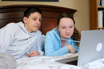 weekend boys teenage girls watch a movie on a laptop attentively focused look at the computer lie on bed touch the laces from the sweater ordinary day First love relationship communication Classmates