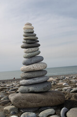 High cairn made of stones on a pebble beach, sea background. Stone's balance