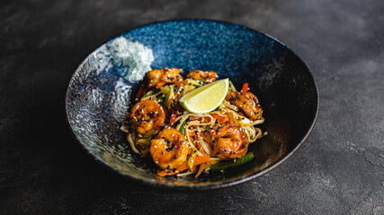 Eastern food. Noodles and shrimp with spicy sauce. Dark background.