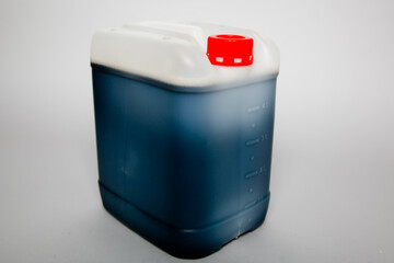 White plastic canister with dark liquid inside and a red lid