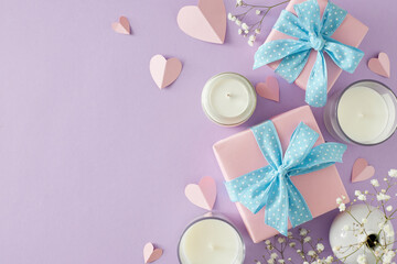 Happy Mother's Day mood concept. Top view photo of present boxes aroma candles gypsophila flowers and paper hearts on soft pastel violet background. Flat lay with empty space for text