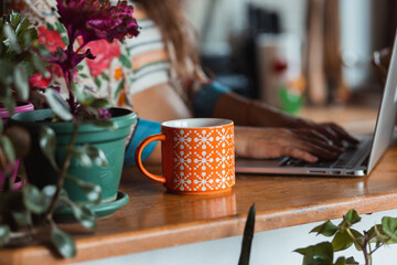 Young pregnant freelancer working on her laptop and drinking coffee.