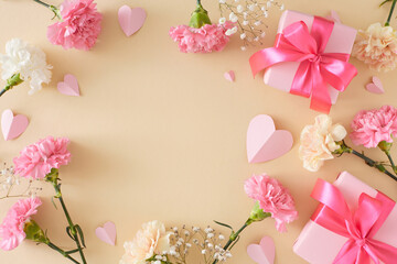 Mother's Day joy concept. Top view photo of gift boxes with bows and pink cream carnations flowers paper hearts on pastel beige background. Flat lay with empty space for text or greeting