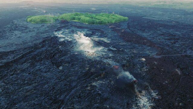 Aerial Kilauea Volcano eruption aftermath with burned residential properties buried black frozen lava field. Consequences of Hawaii eruption with large lava flow, white ashes and smoke above fissure