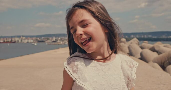 Happy laughing and singing beautiful girl walking near beach shore of Black sea coast, Varna city, Bulgaria 4k slow motion video
