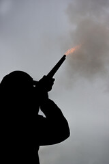 Man shooting a percussion rifle muzzleloader at a clay pigeon target