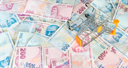 Cost of living concept. Empty cart on a stack of Turkish liras. Inflation rising in Turkey. Economic crisis. Rising costs in daily life