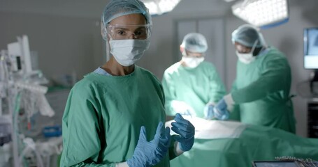 Portrait of diverse surgeons with face masks during surgery in operating room in slow motion