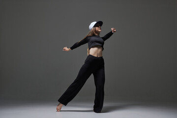 a girl in dark clothes dances and jumps on a dark background background modern dance