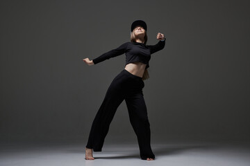 Obraz premium a girl in dark clothes dances and jumps on a dark background background modern dance