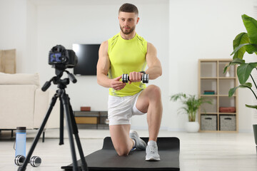 Fototapeta na wymiar Trainer with dumbbell recording workout on camera at home