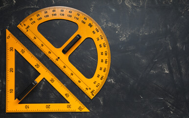 Protractor and triangle ruler on blackboard, flat lay. Space for text