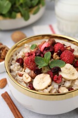 Delicious oatmeal with freeze dried berries, banana, nuts and mint on table, closeup