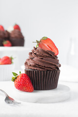 Chocolate cupcake with dark chocolate buttercream and strawberries, double chocolate cupcakes with american buttercream, tall swirl frosting on a cupcake with a strawberry