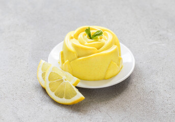 Lemon cream pudding, Panna Cotta in the shape of a rose, on a plate. Light grey background