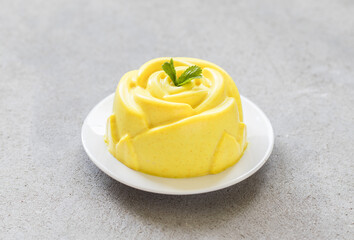 Vegan Lemon Panna Cotta in the shape of a rose, on a plate. Light grey background