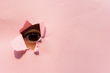 Observing the eye of a baby girl in the hole of pink paper. Eye under the pink paper.	