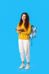 Female student with notebook and backpack on blue background